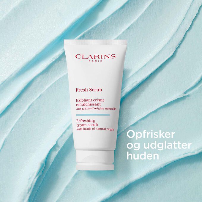 Clarins Fresh Scrub til ansigtet p&aring; en cremet, tekstureret baggrund, der fremh&aelig;ver dens udglattende og opfriskende effekt.