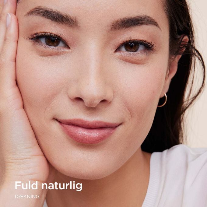 Kvinde if&oslash;rt Clarins Skin Illusion Full Coverage foundation, der viser fuld d&aelig;kning med et naturligt resultat.
