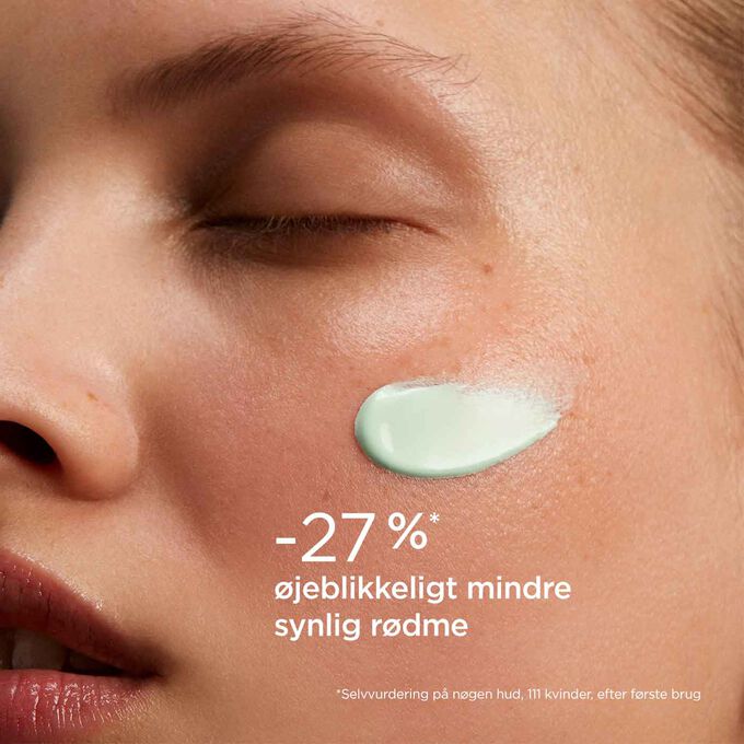 Woman with closed eyes wearing SOS Primer Green by Clarins on her face to illustrate that it reduces redness by 27%.