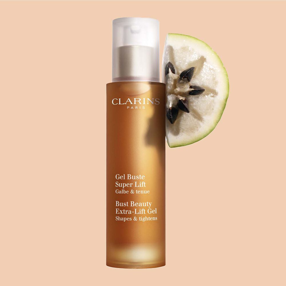 Packshot of a bottle of Clarins Bust Beauty Extra-lift Gel close to a slice of Vu sua fruit on a peach background.