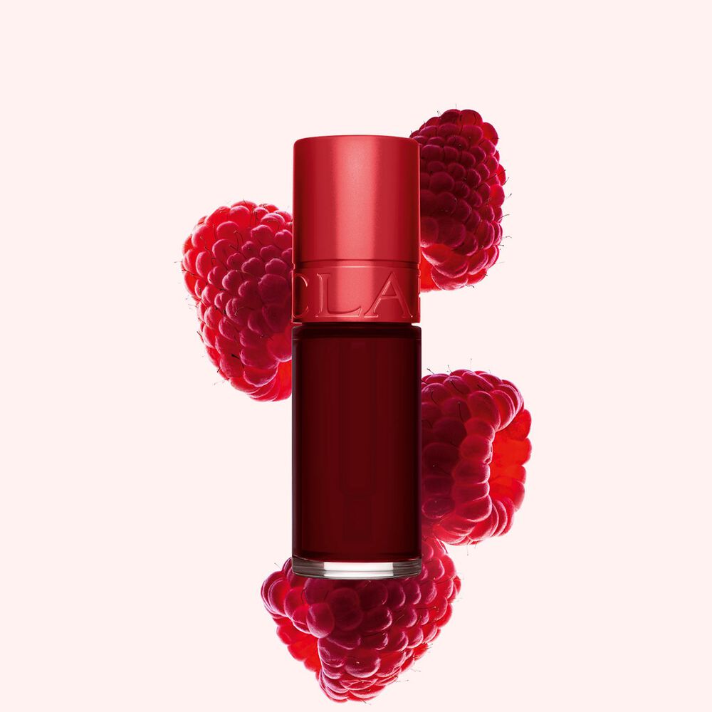 Packshot af Clarins Dark Red Water Lip Stain i nuance 9, placeret ved siden af hindbær på en lyserød baggrund.