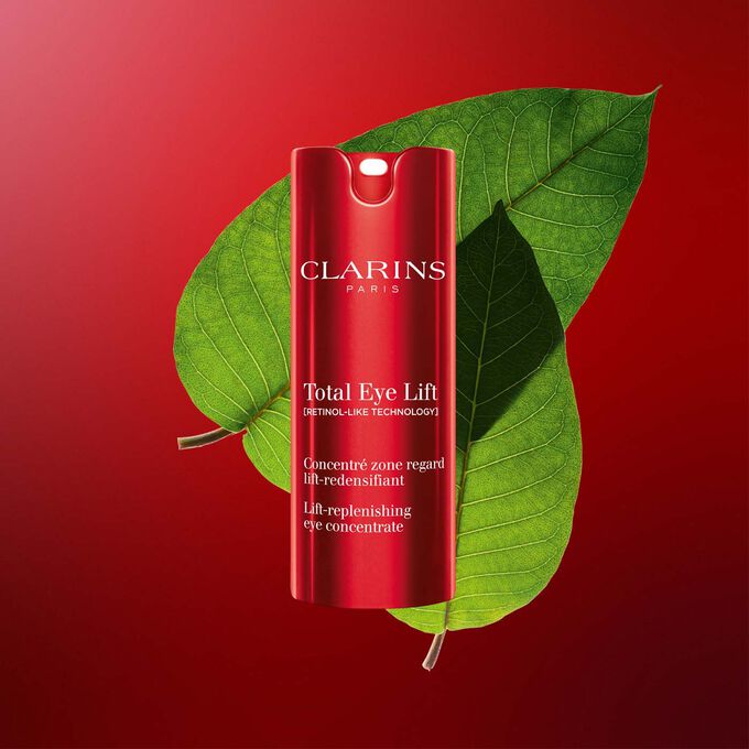 Packshot af Clarins Total Eye Lift anti-age øjencreme med harungana-blade på mørkerød baggrund.