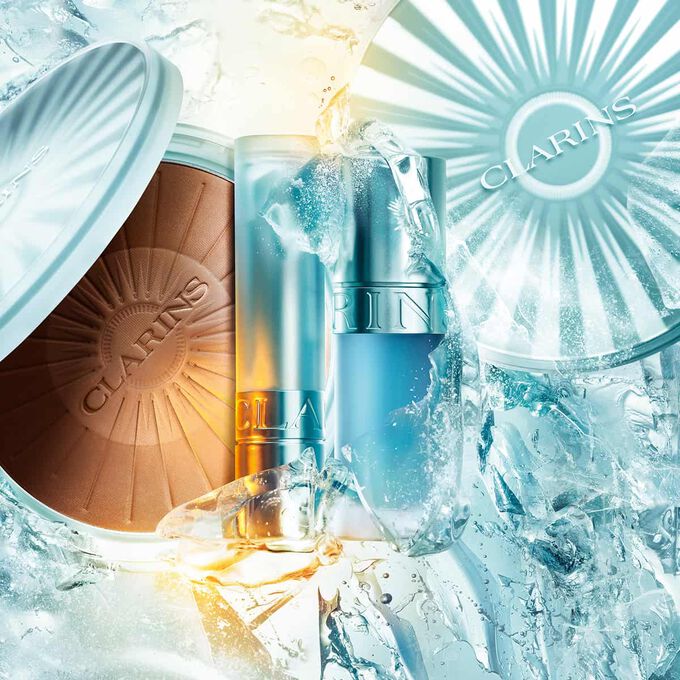 Packshot af Clarins summarkollektion p&aring; is: bronzingpudder, cryo lip oil og k&oslash;lende l&aelig;bepomade, der fremh&aelig;ver sommerens must-haves