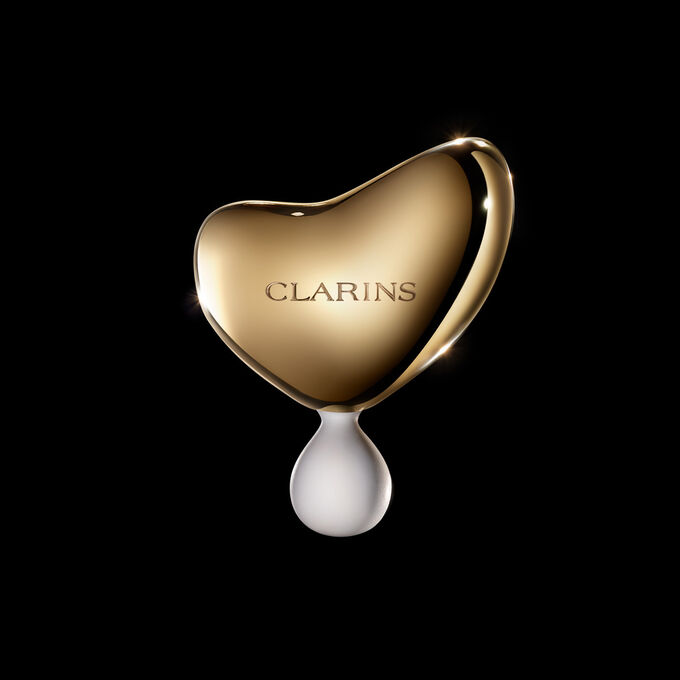Photoshoot of Clarins Precious Massage Tool on dark background.