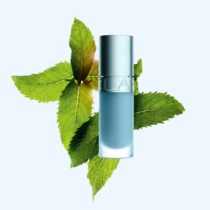 Packshot af Clarins Lip Comfort Oil med ny k&oslash;lende effekt og glansfuld finish, placeret foran mynte for at fremh&aelig;ve dens n&oslash;gleingrediens