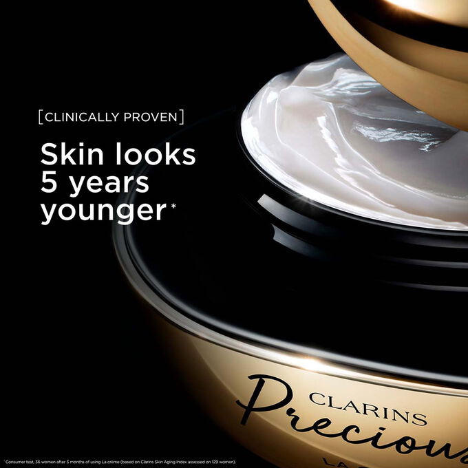 Packshot of Clarins Precious Soft Cream on dark background, with text emphasising its power to make skin appear 5 years younger