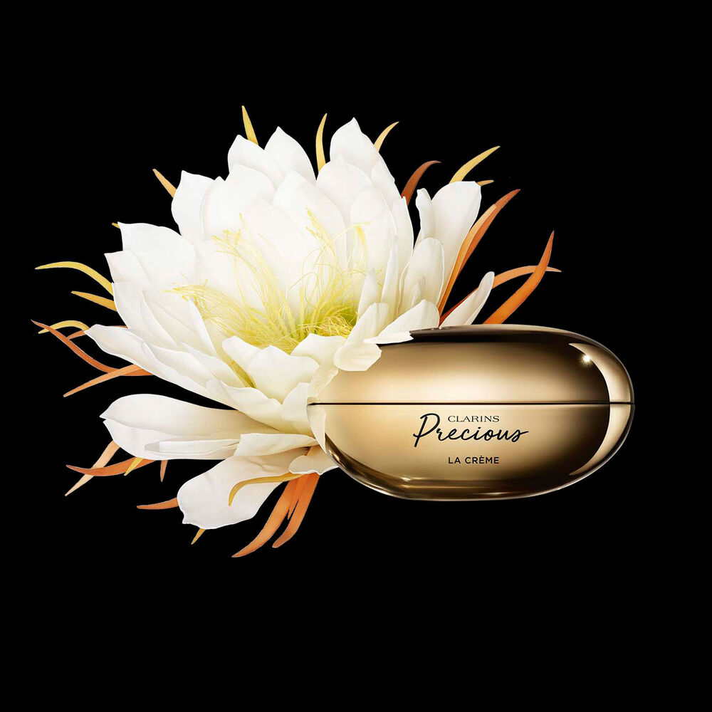 Packshot of Clarins Precious Soft Cream close to a Moonlight flower on dark background.