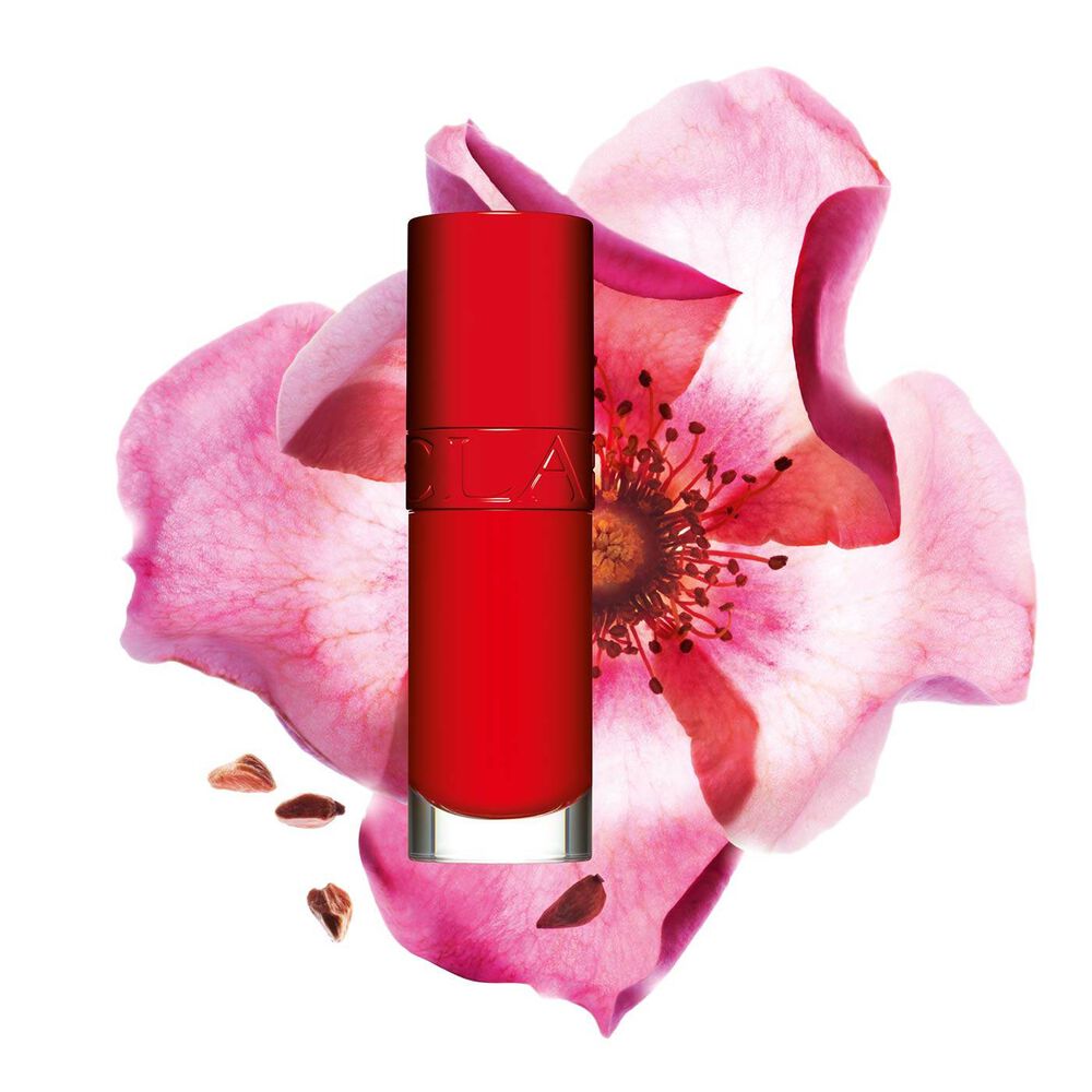 Packshot af Clarins Lip Comfort Oil i Iconic Red, placeret ved siden af en hybenroseblomst på en sort-rød baggrund.